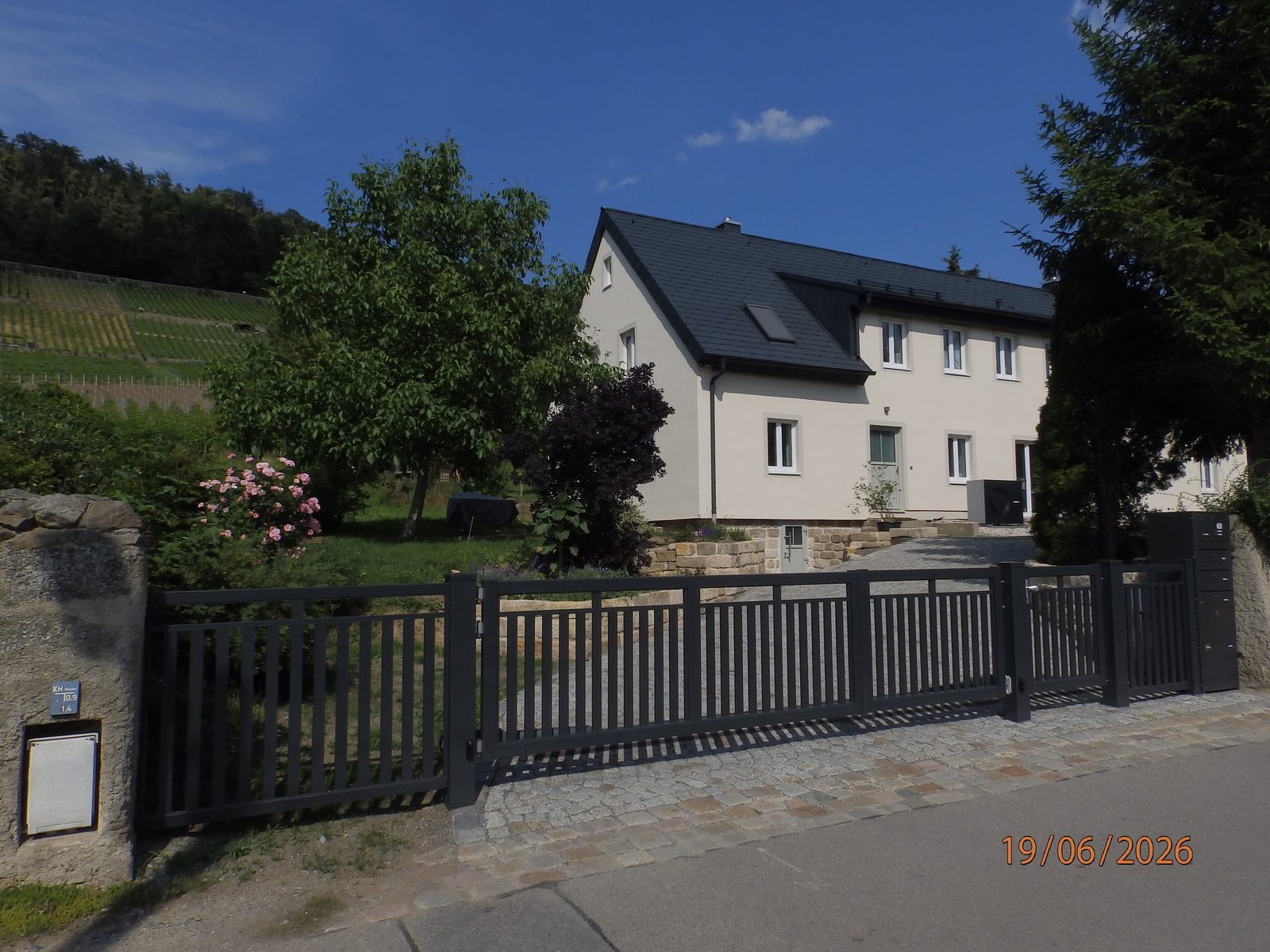 Straßenansicht des sanierten Hauses in Dresden-Pillnitz mit Weinbergen im Hintergrund